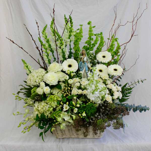 White floral arrangement in a wicker basket with a small statue at center