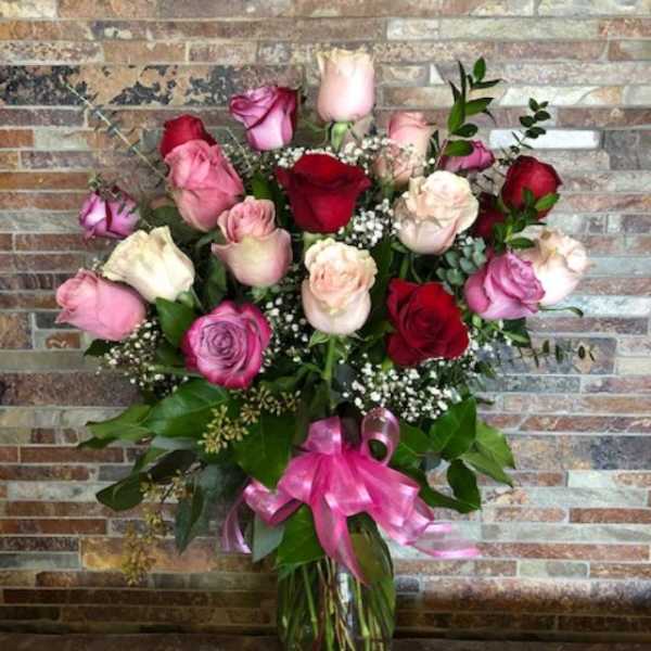 Bouquet of pink and red roses in a glass vase with a pink ribbon