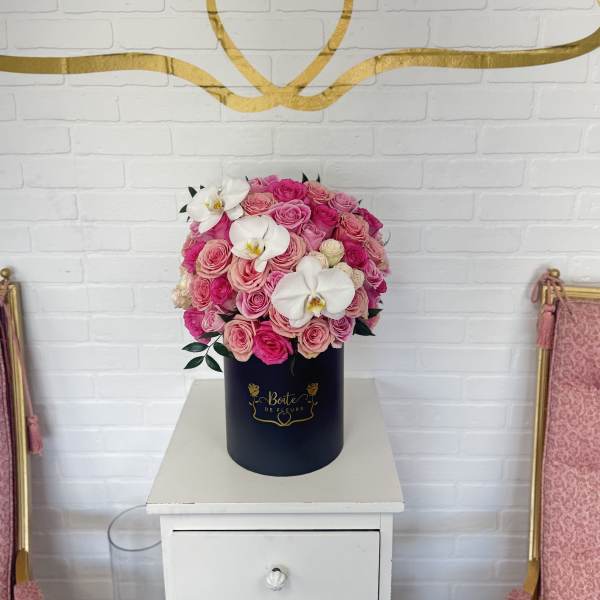 Pink rose arrangement in a navy cylindrical box with white orchids