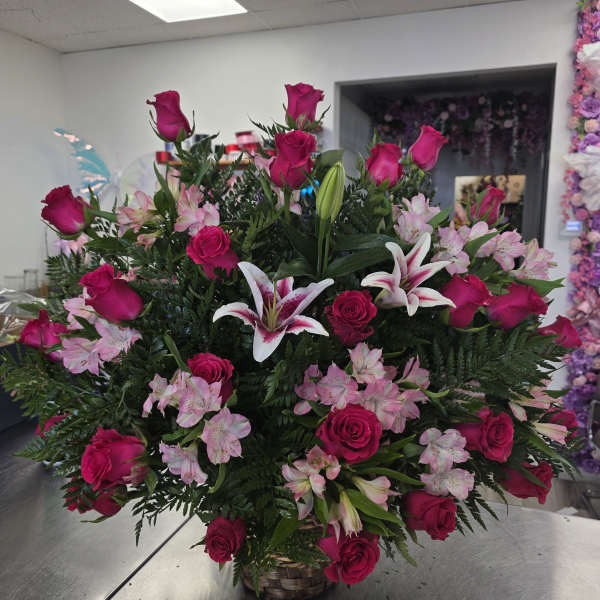 Basket arrangement of hot pink roses, pink lilies, and pale pink flowers