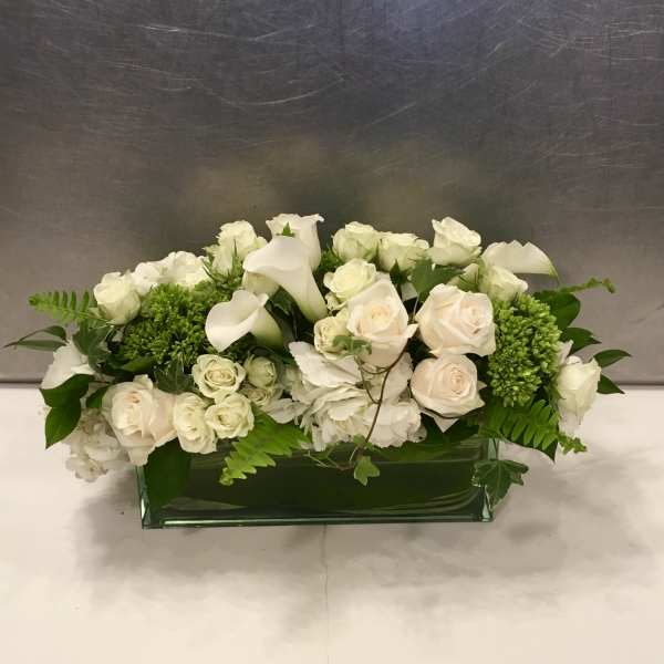 White roses and calla lilies in a low rectangular vase