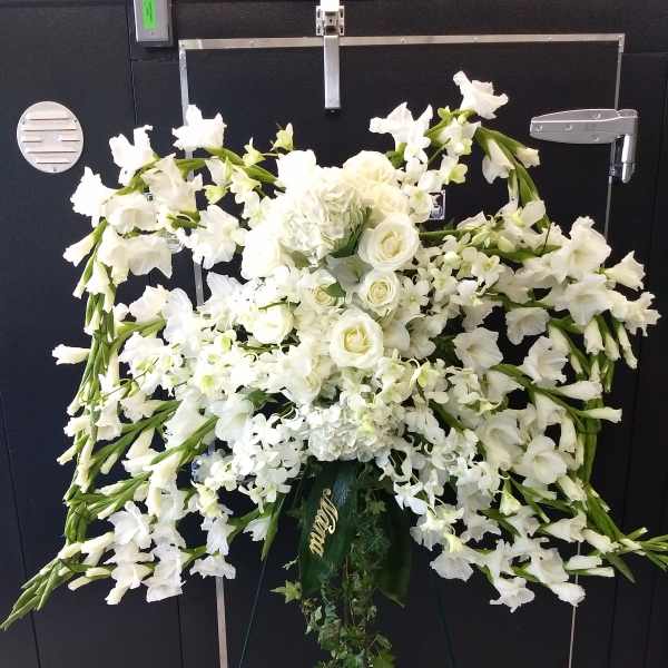 White funeral spray with roses and orchids on a standing easel