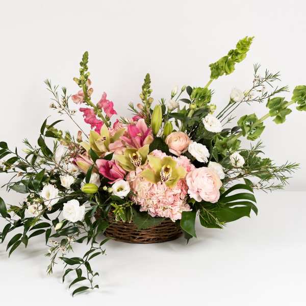 Basket arrangement of pink and white flowers with tall green spikes
