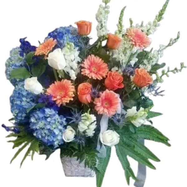 Mixed bouquet with blue hydrangeas, orange roses, and peach gerbera daisies in a basket