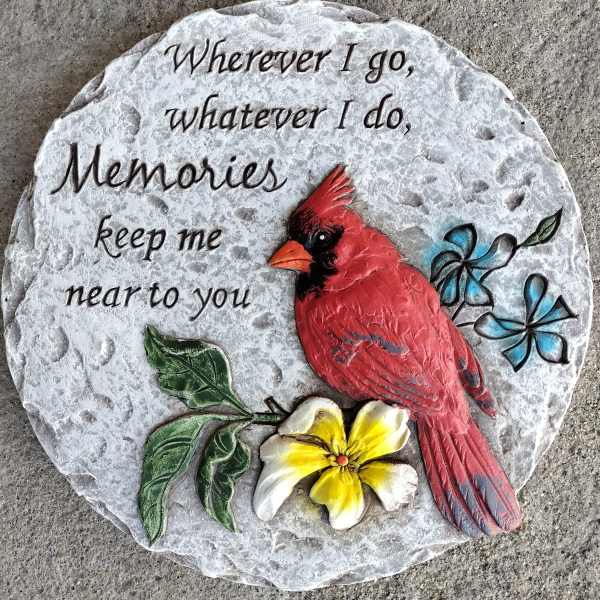 Round memorial stone with a red cardinal, flower, and engraved text