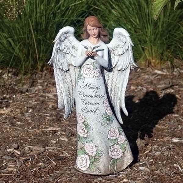 White angel statue with roses and memorial text standing outdoors