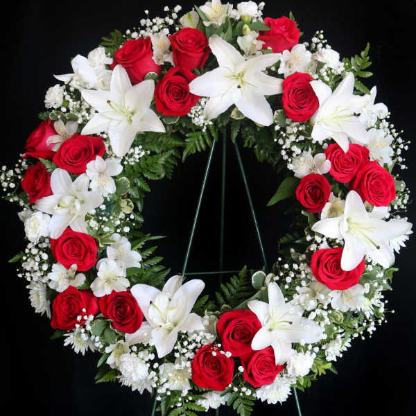 Red roses and white lilies arranged in a circular funeral wreath