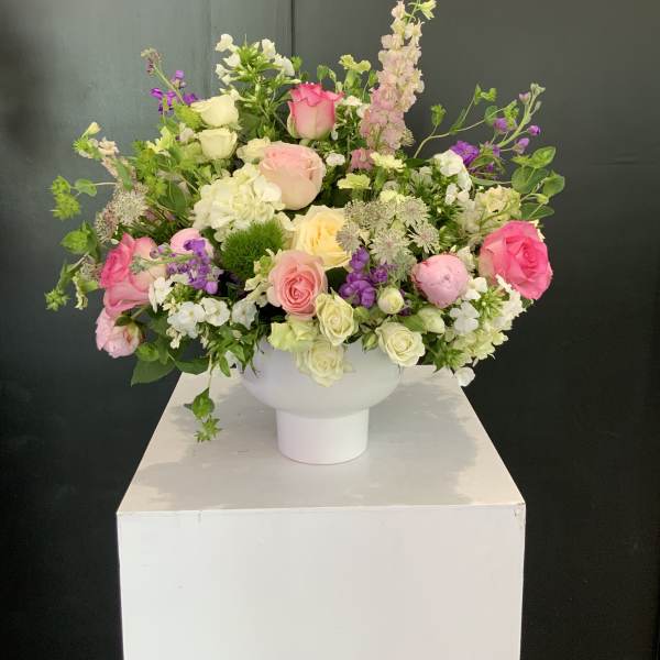 Mixed pink, white, and purple flower arrangement in a white vase