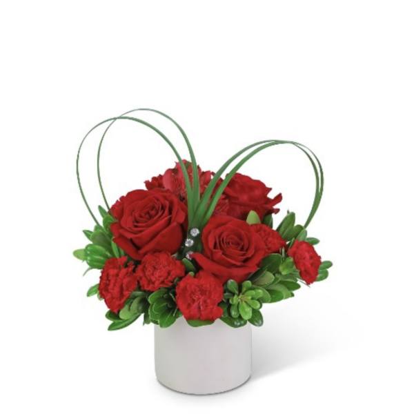 Red roses and carnations in a white cylindrical vase