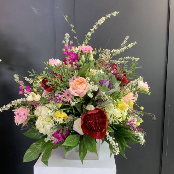 Large mixed bouquet with pink, red, white, and yellow flowers in a square vase