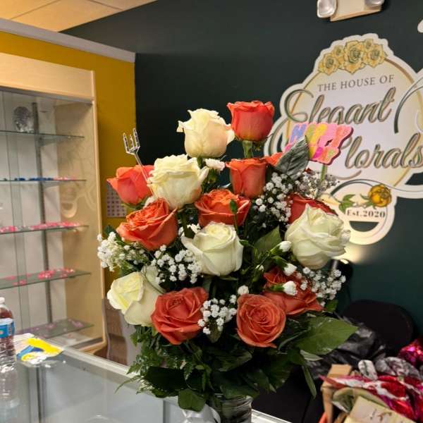 Bouquet of orange and white roses in a glass vase with a white ribbon