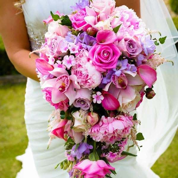 Bride holding a cascading bouquet of pink and purple flowers