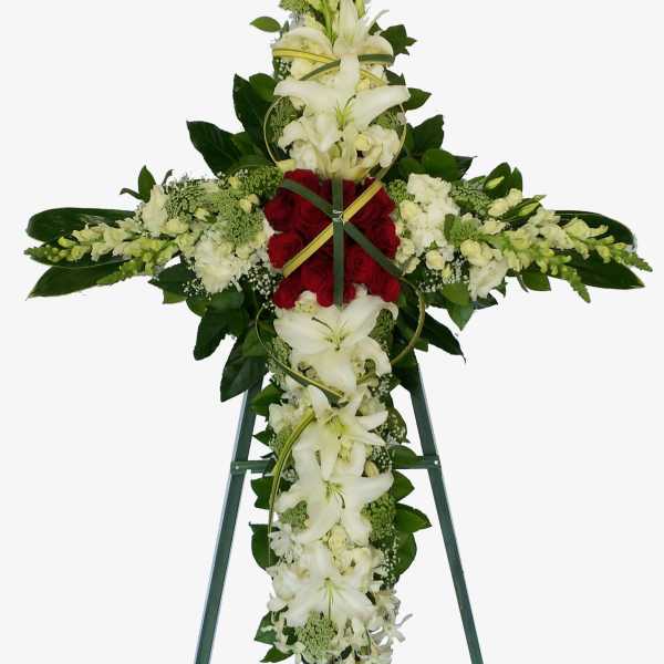 Standing floral cross with white lilies and red roses on an easel