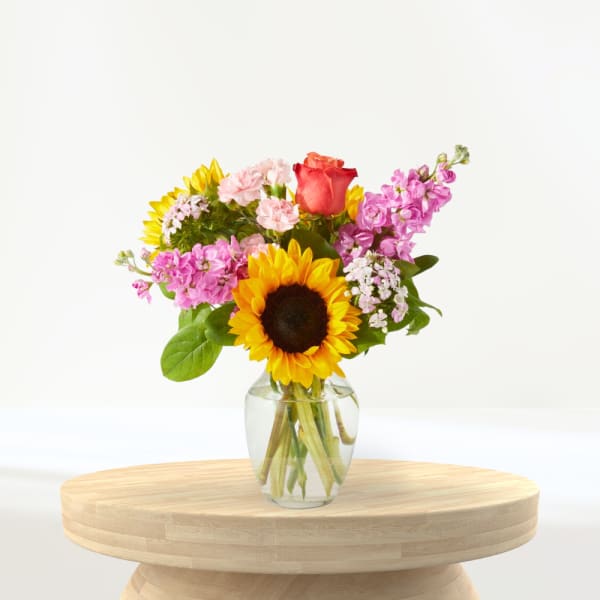 Mixed bouquet with a sunflower and rose in a clear glass vase