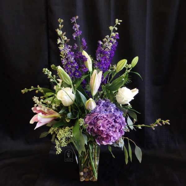 Purple and white floral arrangement in a clear glass vase