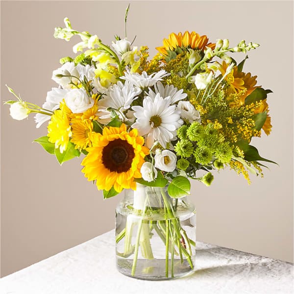 Bouquet of sunflowers, white daisies, and yellow flowers in a glass vase