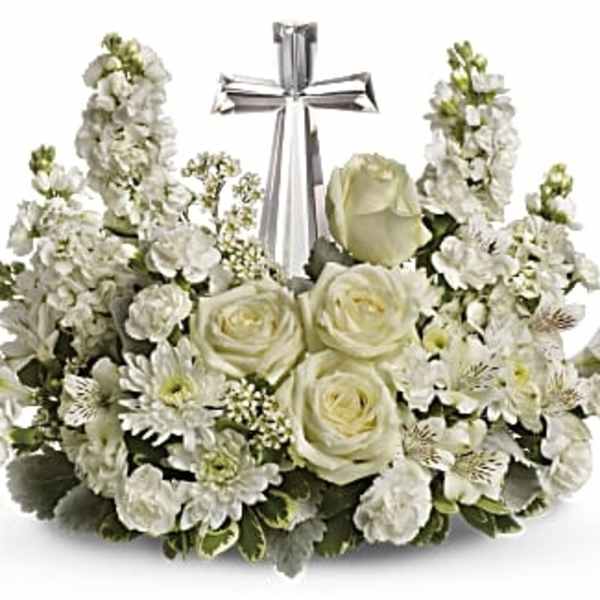 White floral arrangement with roses and stock around a silver cross