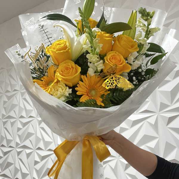 Yellow rose bouquet with lilies and gerbera daisies wrapped in white paper