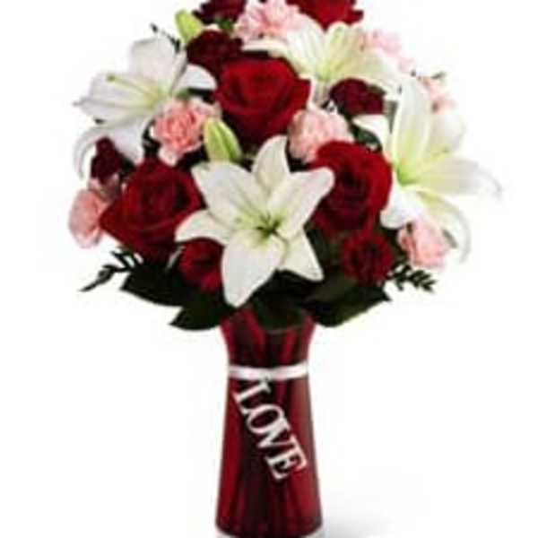 Bouquet of red roses, white lilies, and pink carnations in a red vase