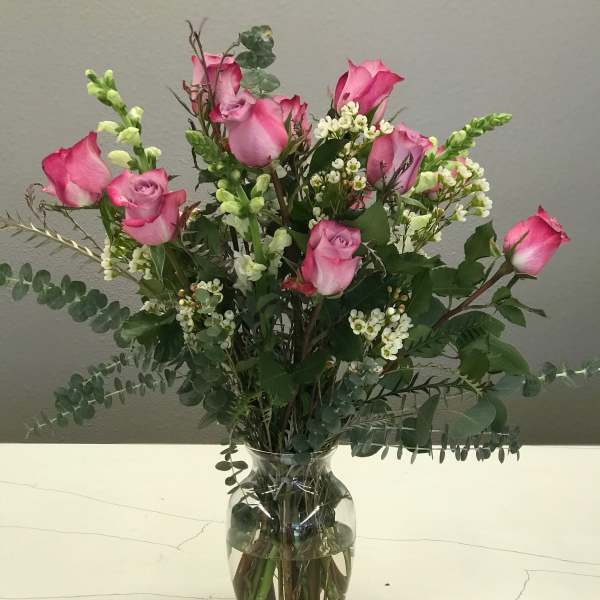 Pink roses in a clear glass vase with white filler flowers