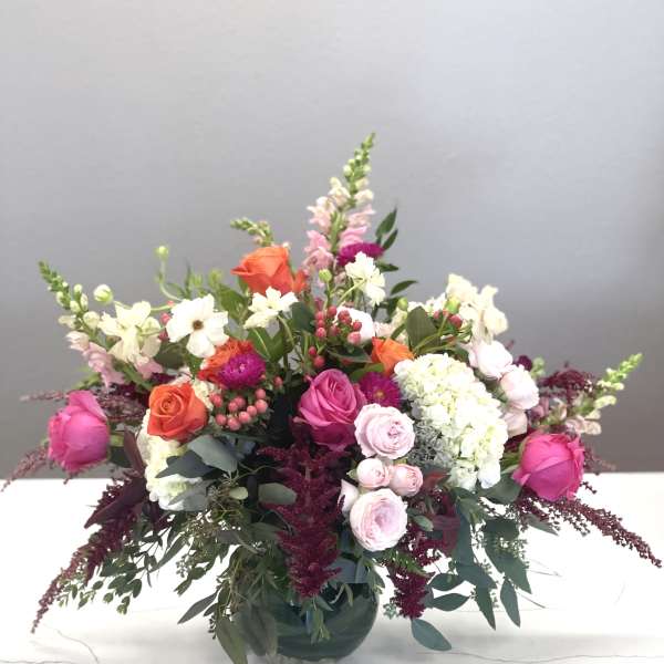 Mixed pink, orange, and white flowers in a glass vase