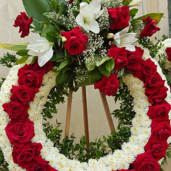 Red and white floral funeral wreath on a wooden easel