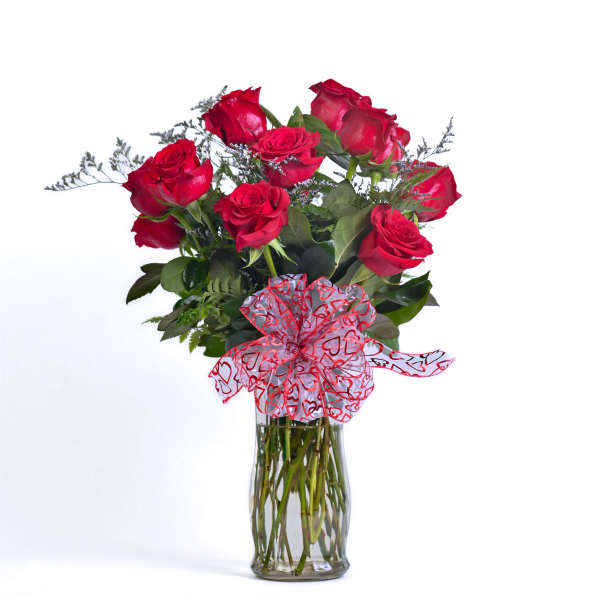 Bouquet of red roses in a clear glass vase with a heart ribbon