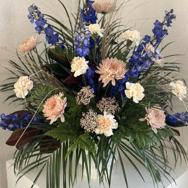 Tall floral arrangement with blue and peach blooms in a vase