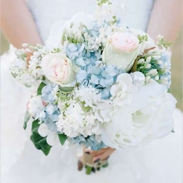 Bride holding a pastel bouquet of white, blue, and pale pink flowers