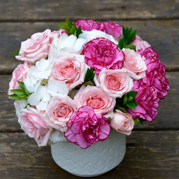 Pink roses and magenta carnations in a white vase