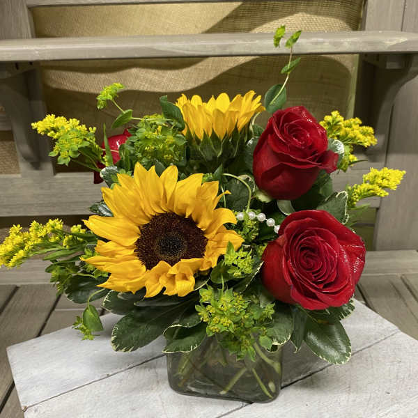 Sunflowers and red roses in a clear glass vase