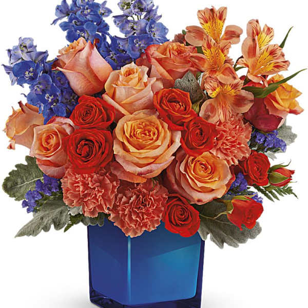 Bouquet of roses, carnations, and blue flowers in a blue glass vase