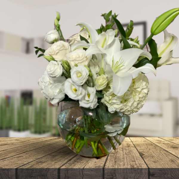White lilies and roses arranged in a round glass vase