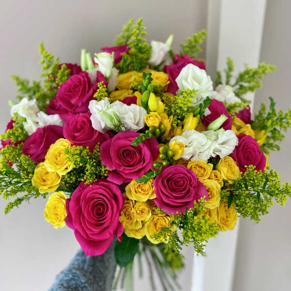 Handheld bouquet of pink, yellow, and white roses