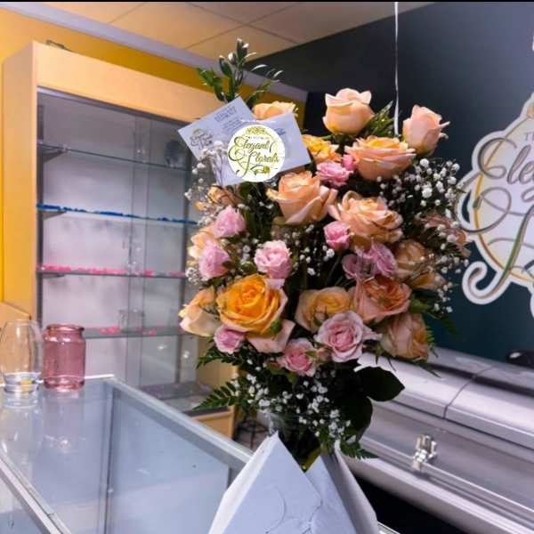 Tall bouquet of peach and pink roses in white wrap