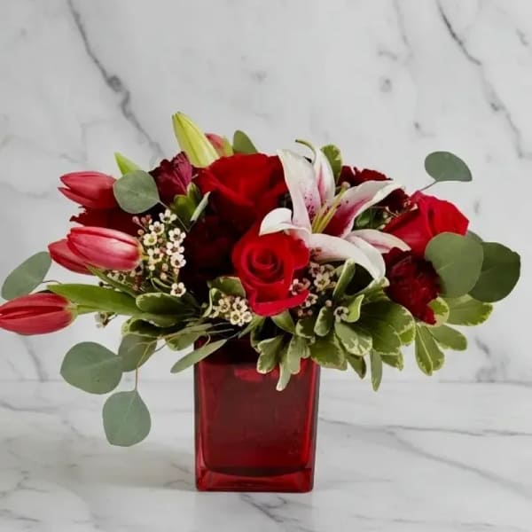 Red roses and lilies in a red glass vase