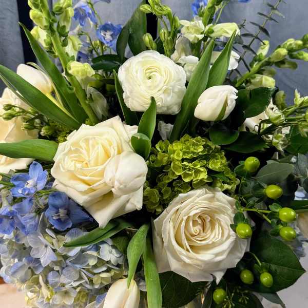 Bouquet of white roses, blue flowers, and green accents