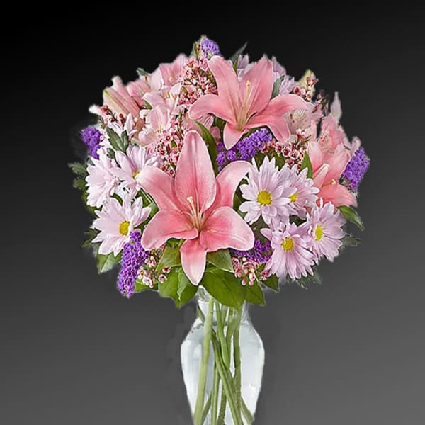 Pink lilies and daisies arranged in a clear glass vase