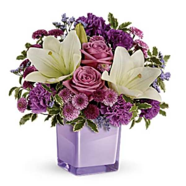 Purple and white floral arrangement in a lavender glass vase