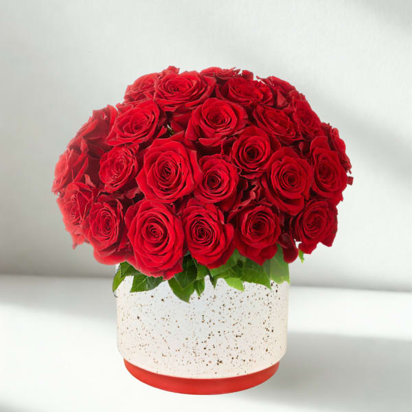 Red roses arranged in a round white speckled vase