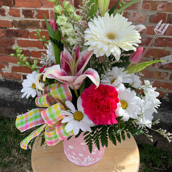 Pink and white mixed flower arrangement in a pink container with a plaid ribbon