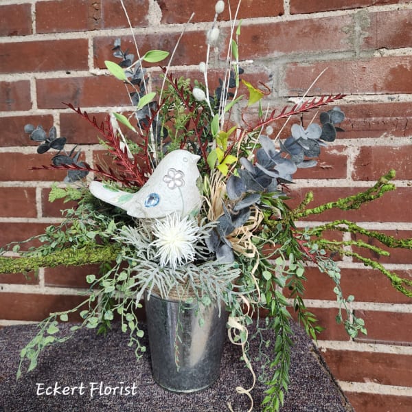 Mixed floral arrangement in a metal vase with a decorative white bird.