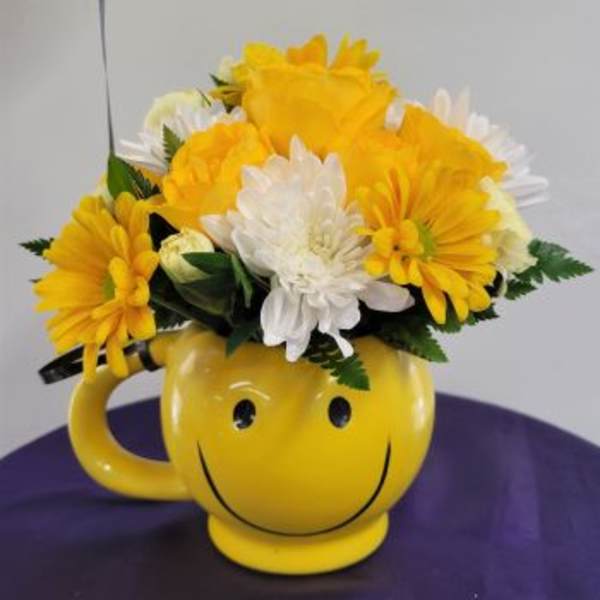 Yellow and white daisy bouquet in a smiley-face mug