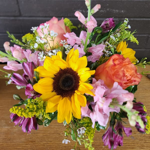 Mixed bouquet with a sunflower, peach roses, and pink blooms