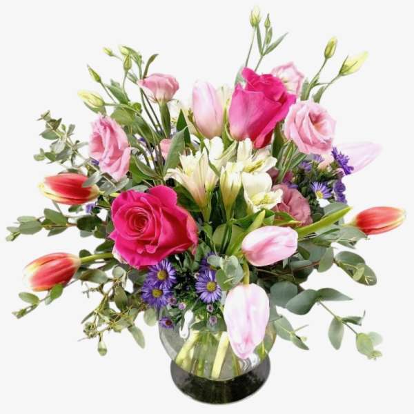 Bouquet of pink roses, tulips, and white lilies in a glass vase