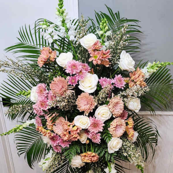 Large standing floral spray with pink and white blooms and palm fronds