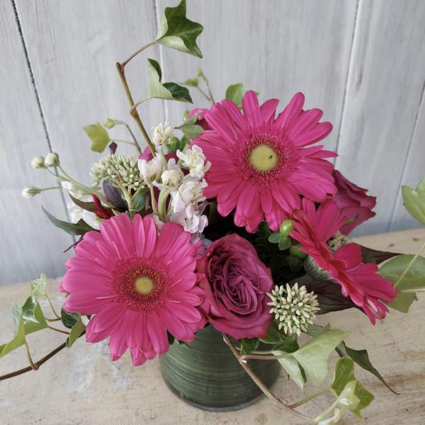 Pink gerbera daisies and roses in a green vase
