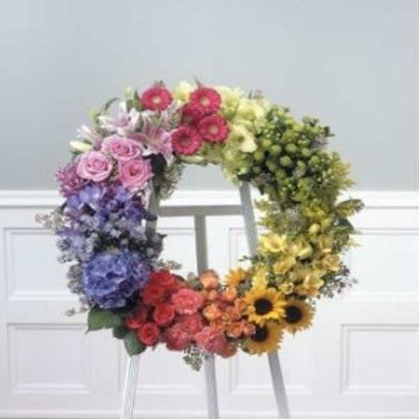 Colorful floral wreath on a stand with mixed blooms in a rainbow gradient