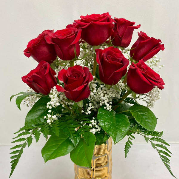 Red roses arranged in a gold vase with baby's breath