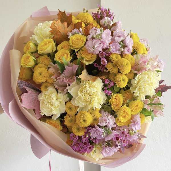 Bouquet of yellow, pink, and cream flowers wrapped in blush paper